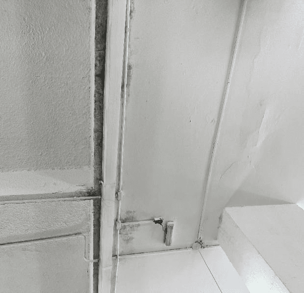 Sinais de umidade e fissuração observados no encontro entre laje, viga e parede.